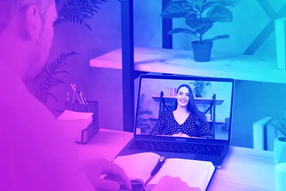 Homme échangeant avec une femme en vision à travers son ordinateur, à l'occasion d'un cours particulier à distance